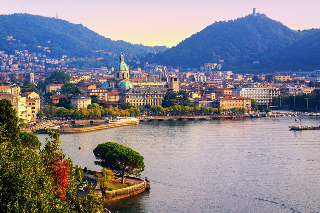 Como city historical town center and Alps mountains on Lake Como, Italy, in warm sunset light